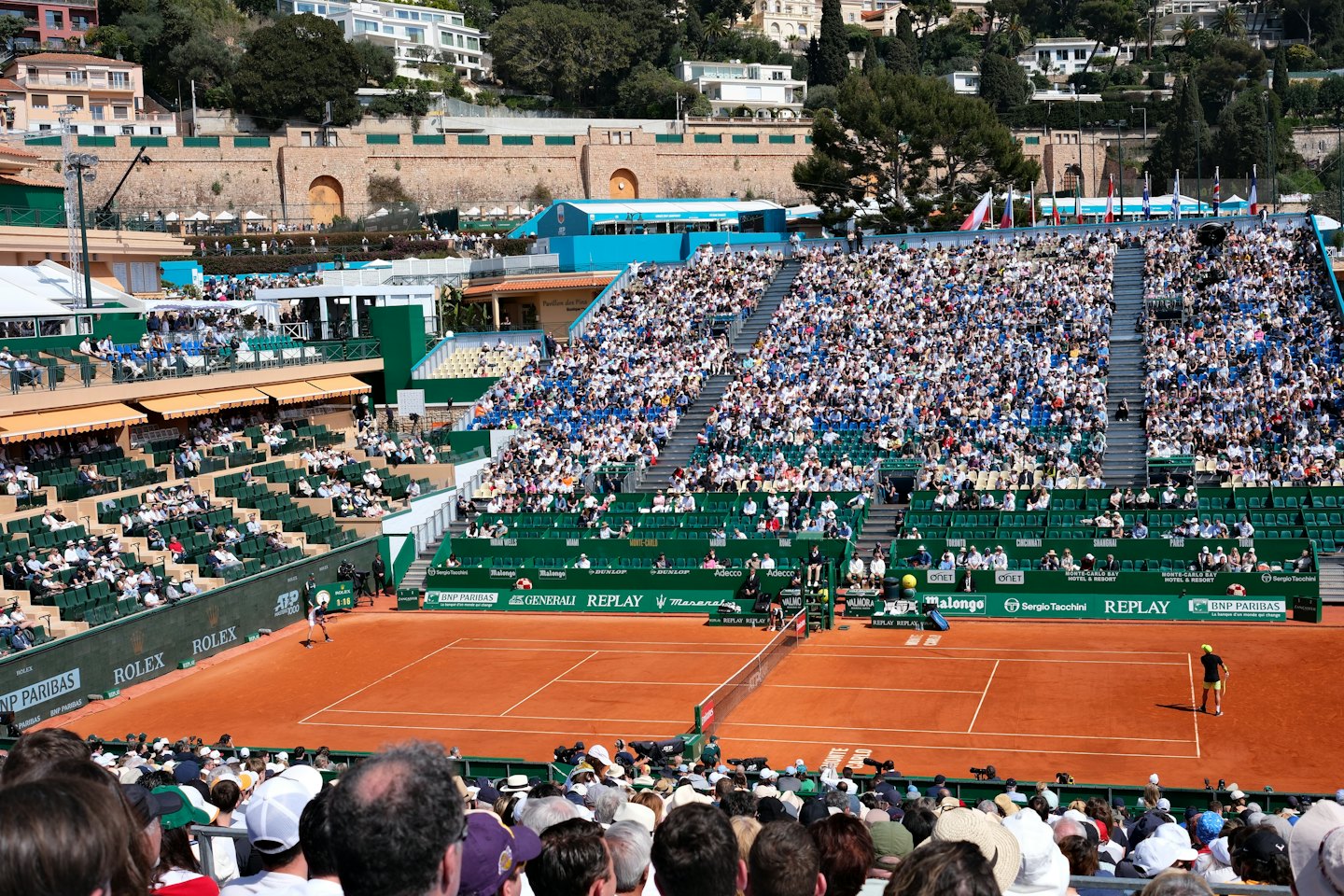 Zwei Tennisspieler spielen in einem Stadion auf einem Sandplatz.